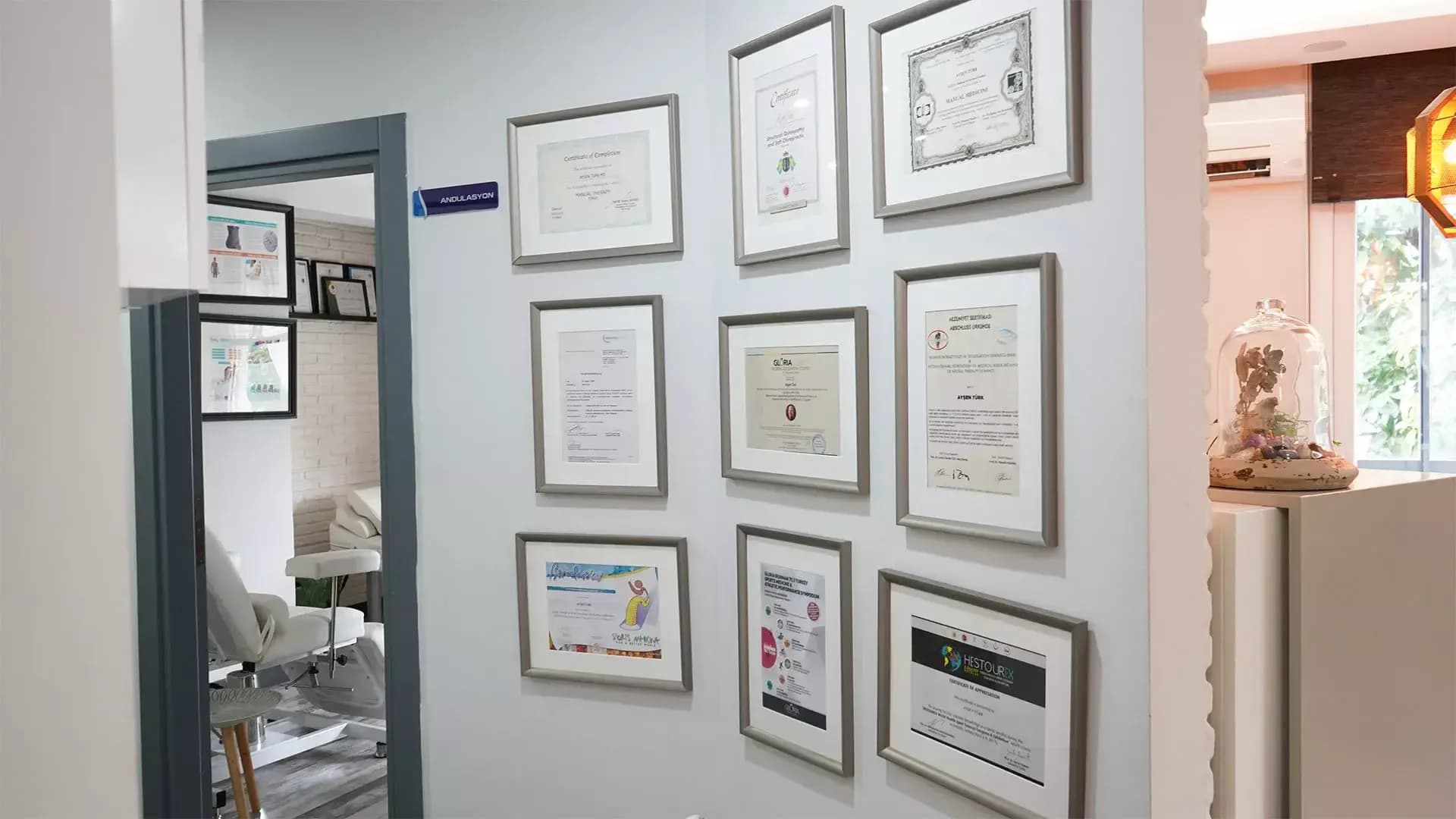 Duvarda sıralı manuel tıp, osteopati ve nöralterapi sertifikaları, yanında andülasyon odası kapısı