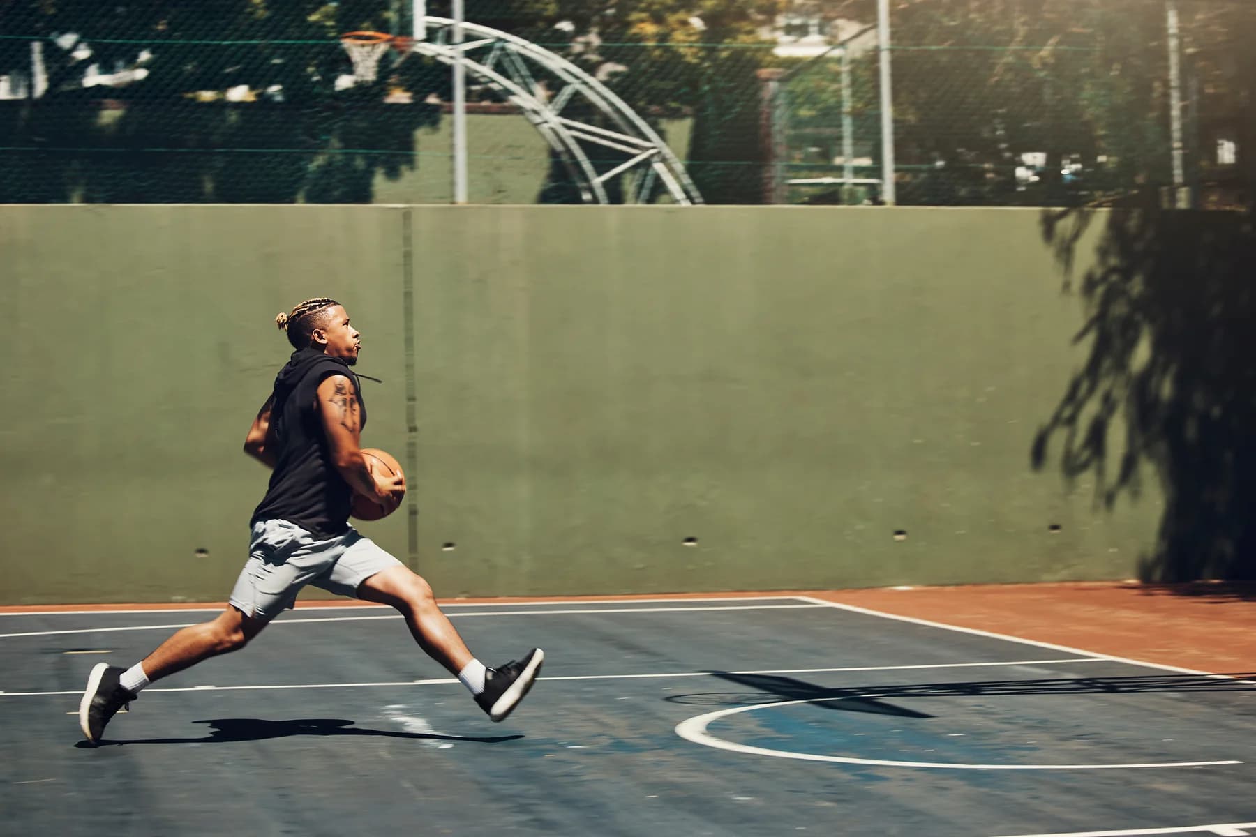 Temsili stok fotoğraf: açık basketbol sahasında topla koşan yetişkin sporcu.